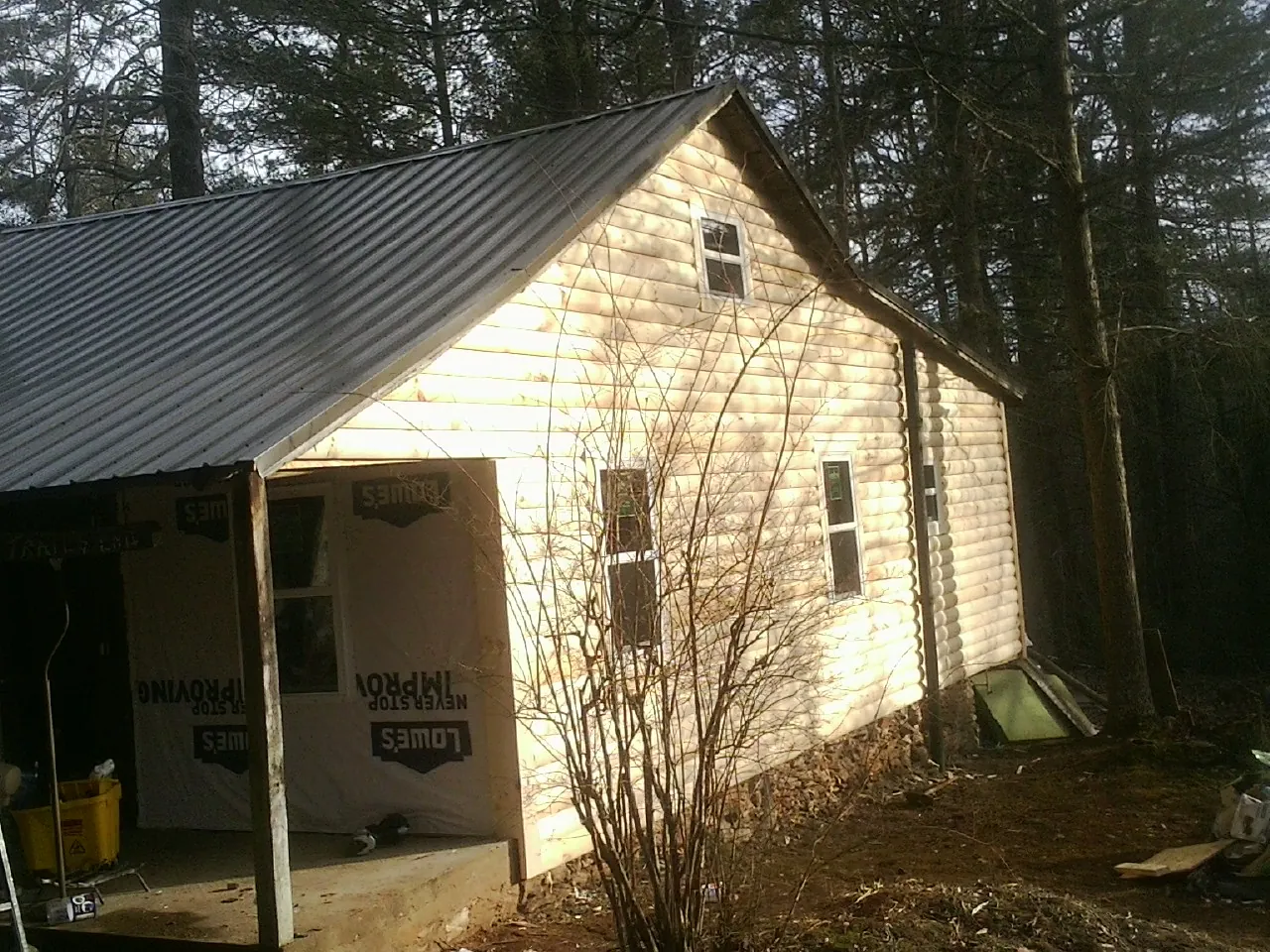 Log siding gable end under a dark metal roof edge in Port Norris