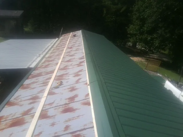 Old rusted panels beside newly installed green metal roofing — Wind Damage Roof Repair by Roofing Brothers in Port Norris