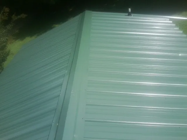 New green metal panels meeting at the ridge of a roof — Flat Roof Repair work by our crew in Port Norris