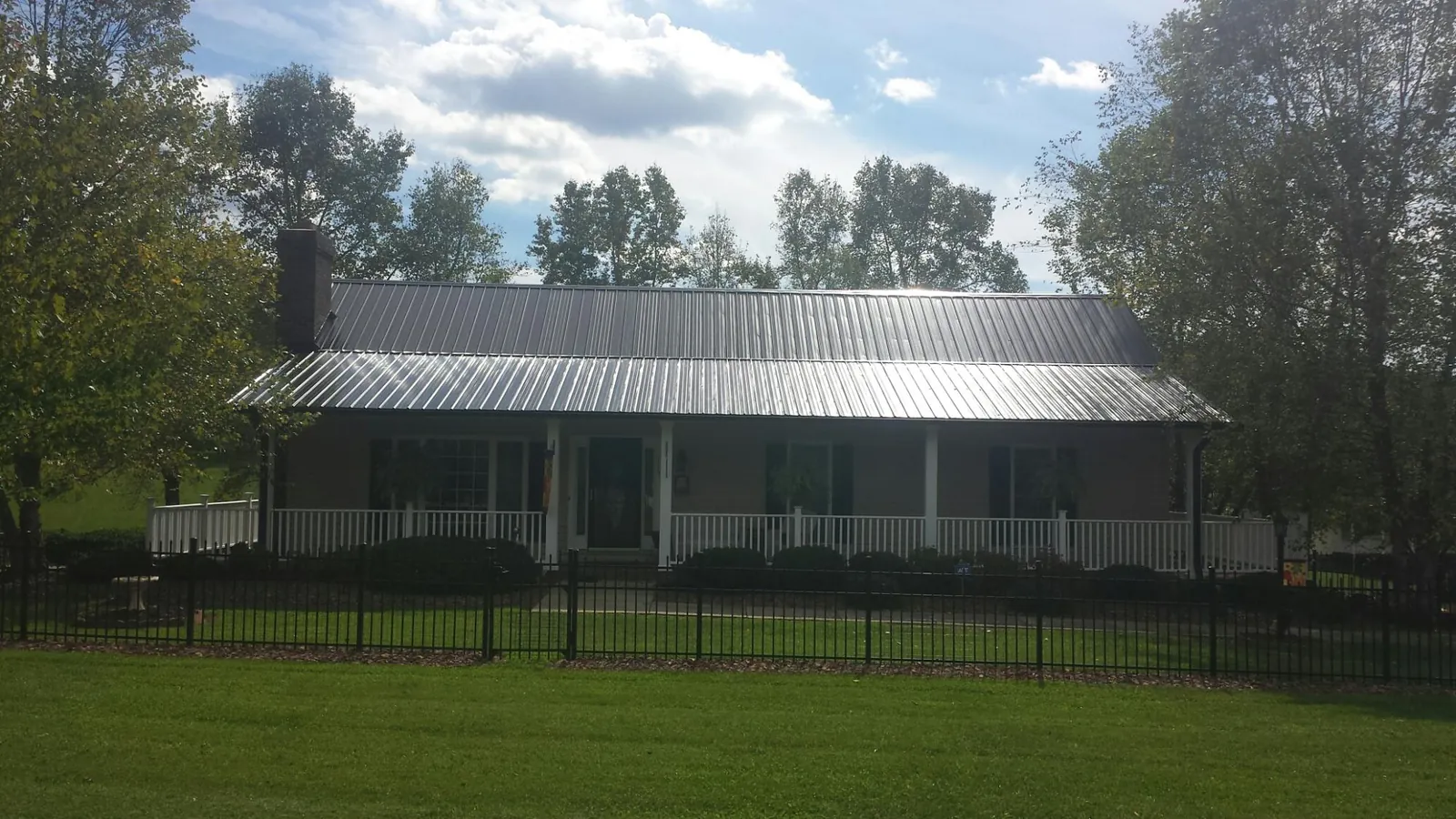 Gray metal roof on a brick ranch with a full width front porch — Gutter Guard Installation work by our crew in Port Norris
