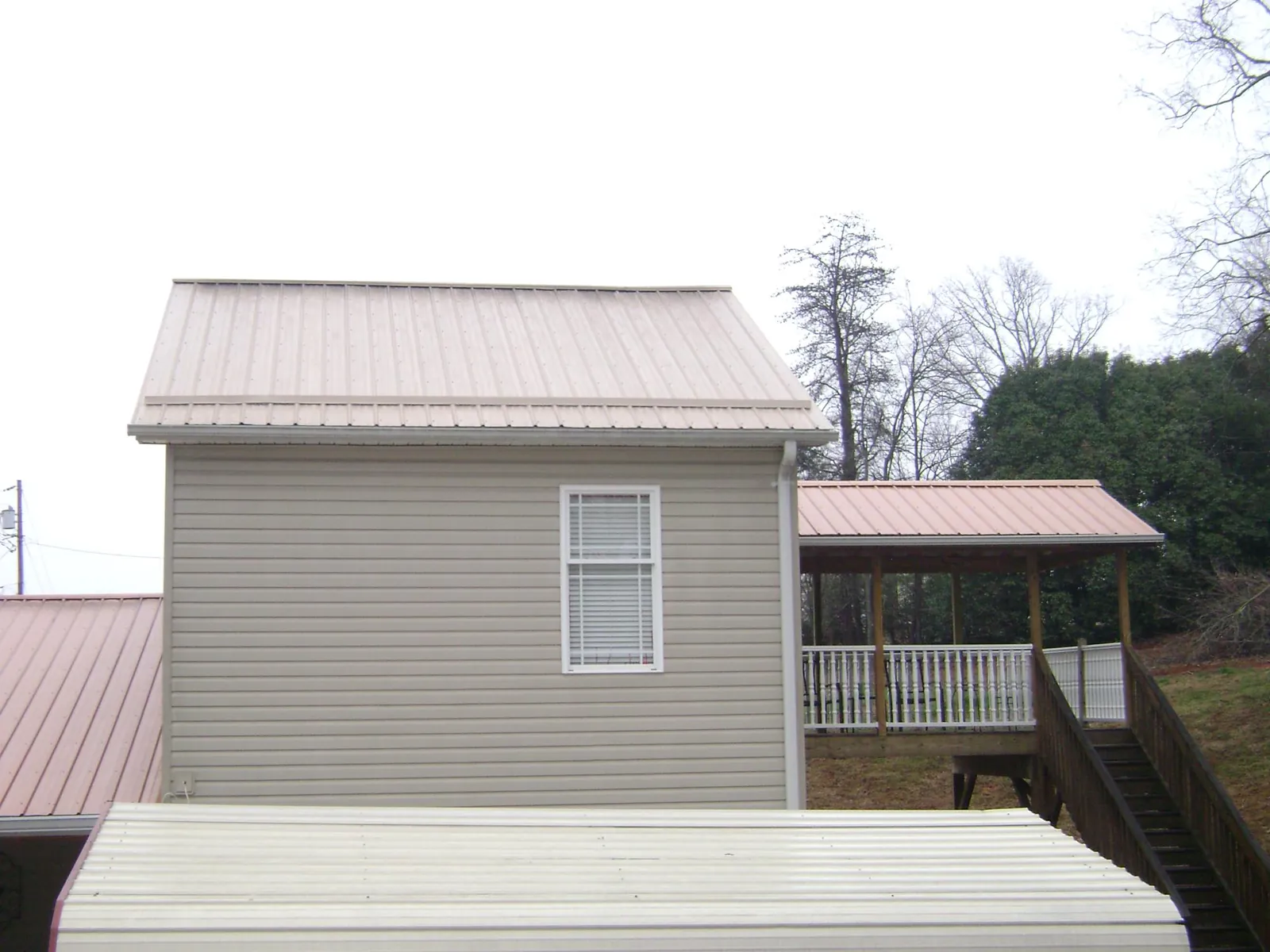 Tan metal roofs on a two story addition and attached porch, from a Roof Replacement job in Port Norris