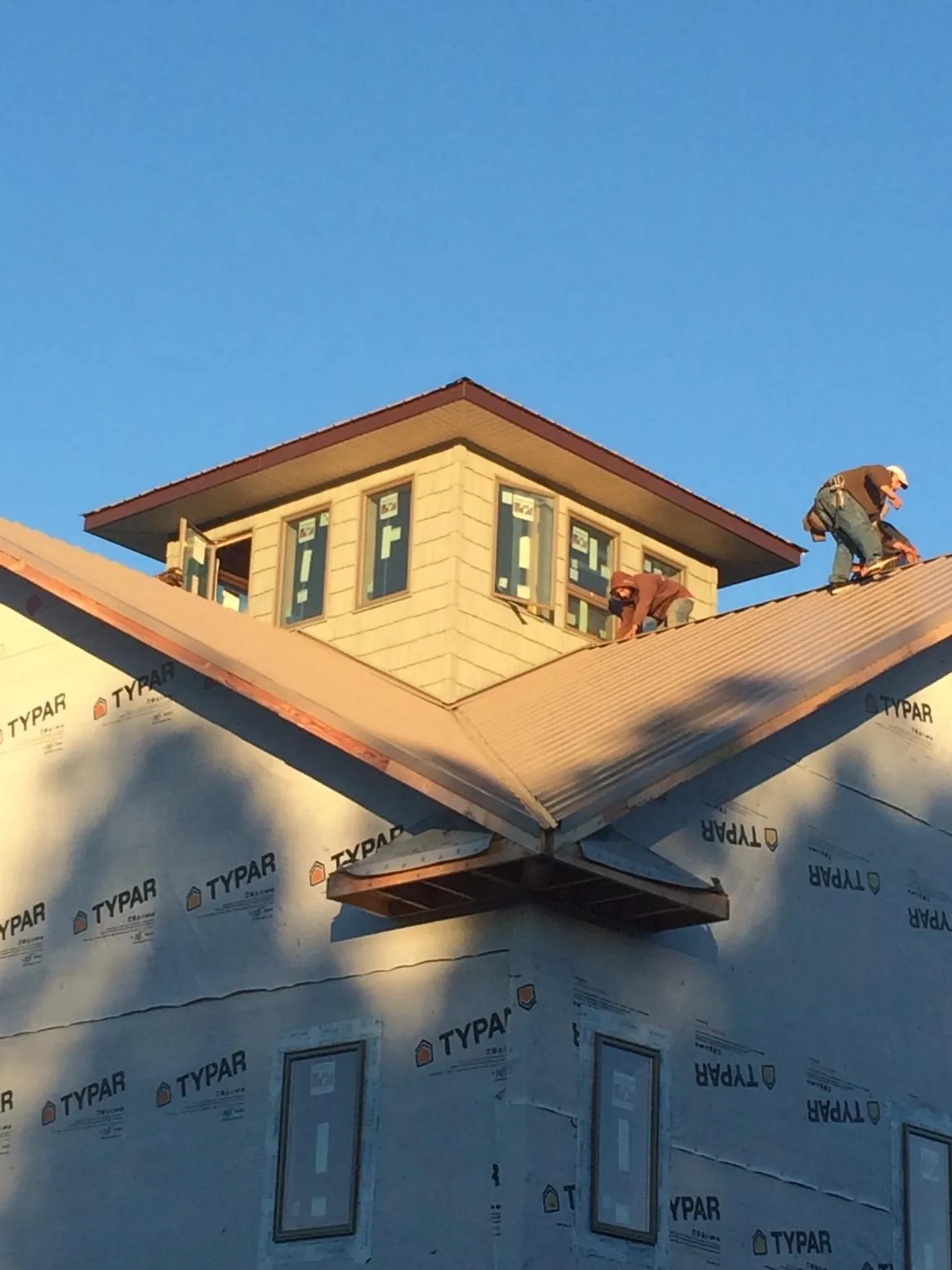 Roofers working around a rooftop cupola on a new metal roof at sunset — Roof Waterproofing in Port Norris by Roofing Brothers